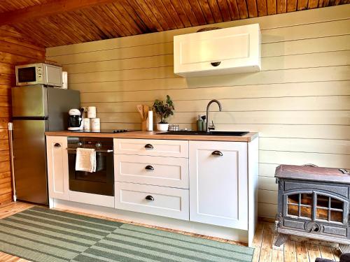  La cuisine est équipée de placards blancs et d'un réfrigérateur. dans l'établissement Chalet de la Prairie - Terrain privé - Bain Nordique, à Hamars