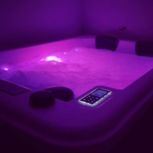 a hot tub with a cell phone in a purple room at My Suite in Bourgoin