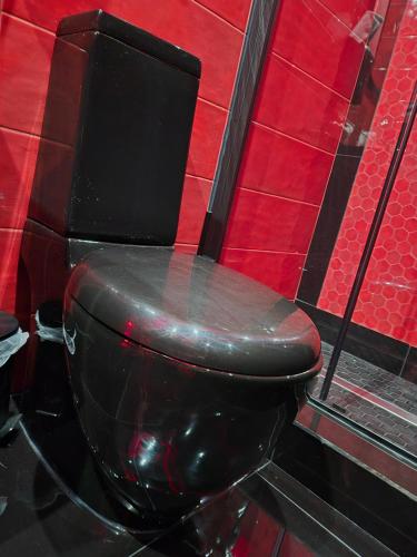 a black toilet in a bathroom with a red wall at Albicocche house Catania in Catania
