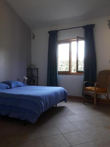 une chambre avec un lit, une fenêtre et une chaise dans l'établissement Maison au calme dans la verdure, à Raucoules