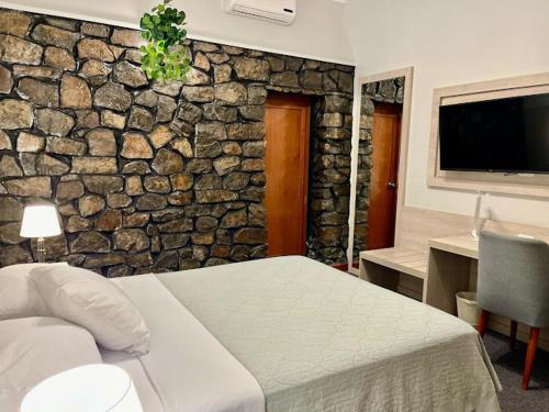 a bedroom with a stone wall with a bed and a desk at Hotel La Villa Mollendo in Mollendo