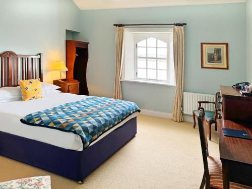 a bedroom with a bed and a desk and a window at Stella Maris Shore House in Ballycastle