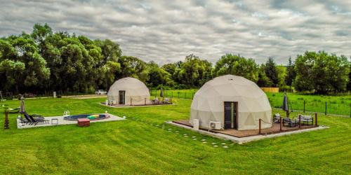 two domed tents in a field with a pool at Glamping nad Sanem in Krzemienna