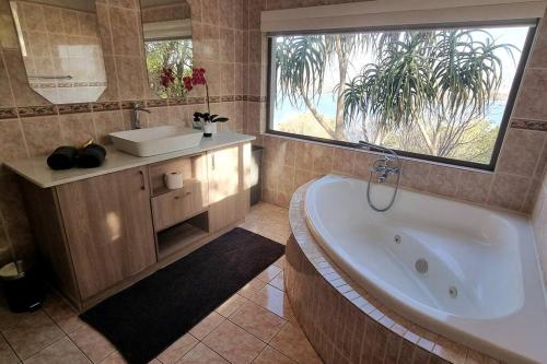 a bathroom with a tub and a sink and a window at Waters View Villa, 5 Bedroom House in Hartbeespoort
