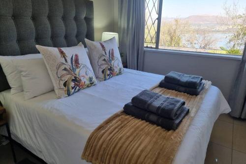 a bed with two towels on it with a window at Waters View Villa, 5 Bedroom House in Hartbeespoort