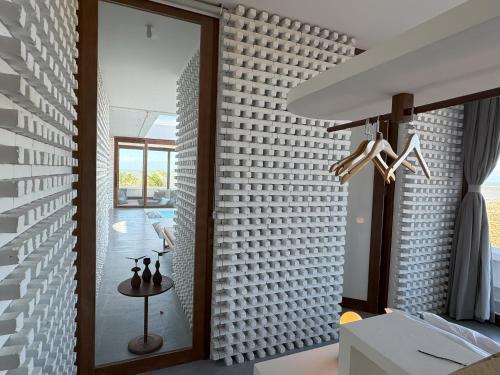 a room with a white brick wall with a glass door at Pousada Mestizo in São Miguel do Gostoso