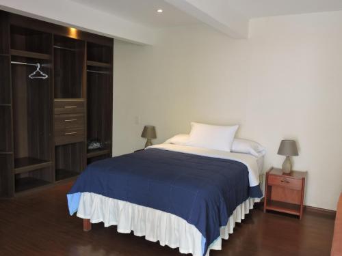 a bedroom with a bed with a blue and white blanket at Hotel La Villa Mollendo in Mollendo