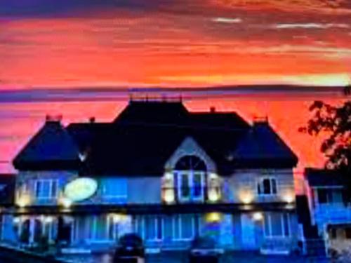 a house with lights in front of a sunset at Motel Belvedere in Saint-Siméon