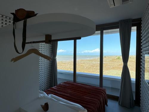 a bedroom with a bed and a view of the beach at Pousada Mestizo in São Miguel do Gostoso