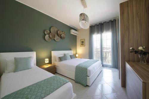 a hotel room with two beds and a window at Villa Merilusi Apartments in Fontane Bianche
