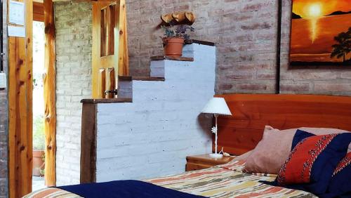 a bedroom with a bed and a brick wall at Carpe Diem Cabañas & Suites in El Bolsón