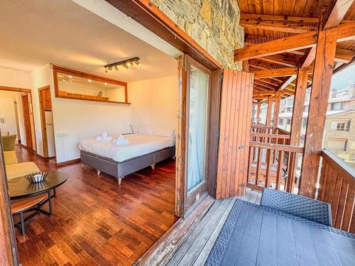a bedroom with a bed in a room with wooden floors at Barthe Holidays I Acogedor estudio en El Tarter 4PAX I Rústico, Vistas al valle, Parking I Esquirol in El Tarter