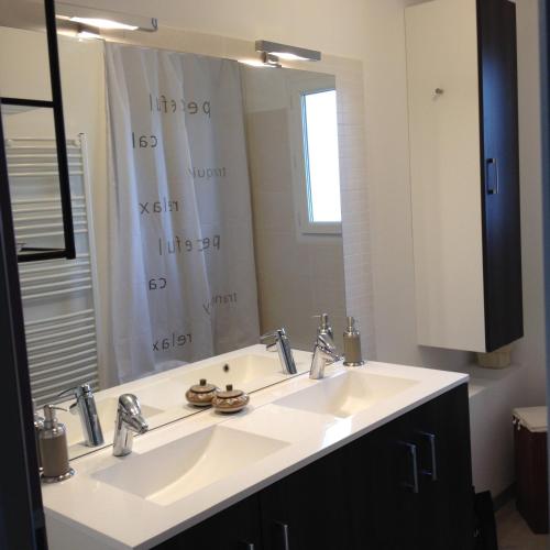 une salle de bain avec un lavabo et un grand miroir dans l'établissement Maison contemporaine avec piscine proche mer, à Baillargues