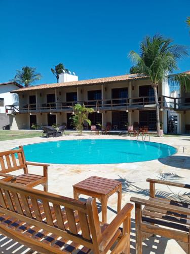 a resort with a swimming pool and two benches at Hotel Pousada Cumbuco Gold in Cumbuco