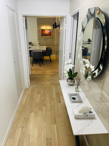 Cette chambre comprend un miroir et un comptoir blanc avec une table. dans l'établissement 4P luxe 200m de Paris vue Sacré Cœur, à Saint-Ouen