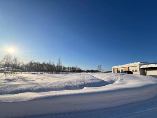 a field covered in snow with the sun in the background at サスティナブルハウス in Kuriyama