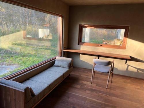 a room with a window with a bench and a chair at サスティナブルハウス in Kuriyama