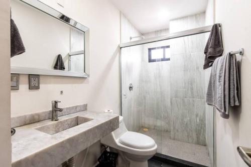 a bathroom with a shower and a toilet and a sink at Elegante depa frente al malecón y cerca del centro in Mazatlán