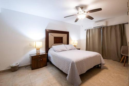 a bedroom with a bed and a ceiling fan at Elegante depa frente al malecón y cerca del centro in Mazatlán