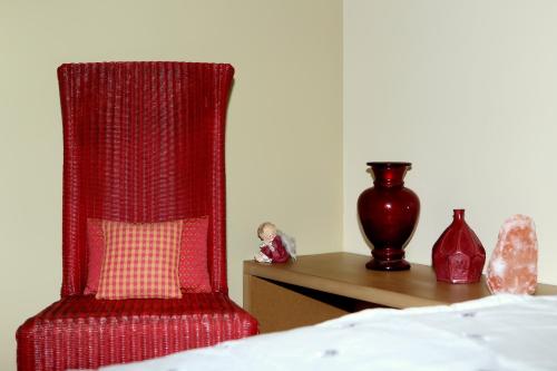 a red chair sitting next to a table with a vase at Aux Pierres Magiques in Saint-Laurent-de-Chamousset