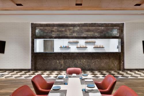 a dining room with a table and red chairs at Courtyard by Marriott Siliguri in Siliguri