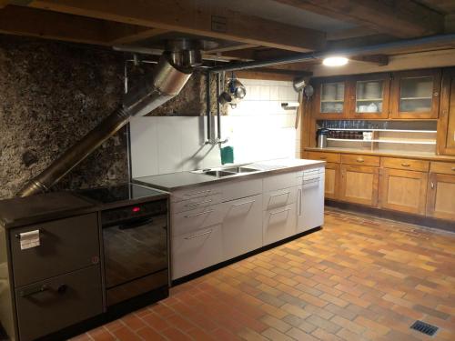 a kitchen with white cabinets and a stove top oven at Staldenhaus Riggisalp in Plaffeien