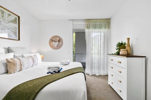 1 dormitorio blanco con 1 cama y vestidor en Coastal Harbour Lights I Pool, Gym & prime Location, en Cairns
