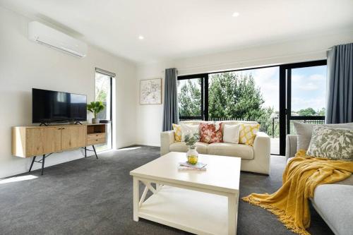 a living room with a couch and a tv at Riverview Retreat-4 bedrooms Brand New House In Hamilton in Hamilton