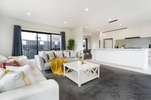 a living room with a white couch and a table at Riverview Retreat-4 bedrooms Brand New House In Hamilton in Hamilton