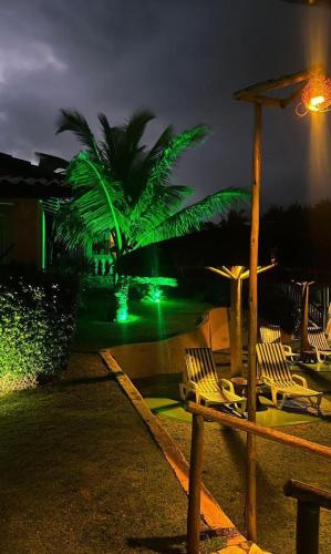 a group of lawn chairs and a palm tree at night at Pousada Luar da Praia in Imbassai