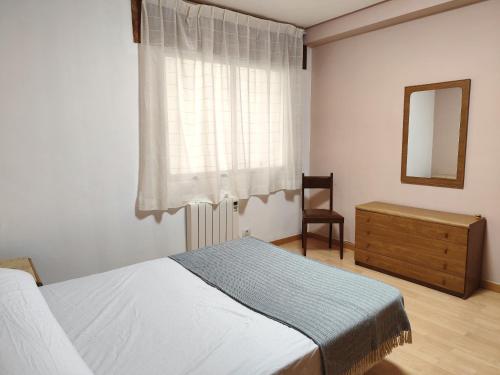 a bedroom with a bed and a dresser and a window at Piso de Alba in Chantada