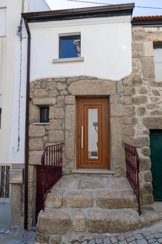 a stone house with a wooden door and stairs at Casa da Carqueija in Valezim