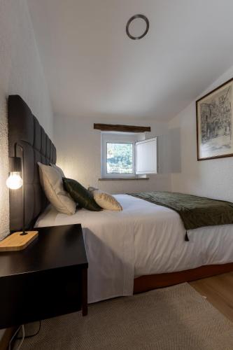 a bedroom with a large bed with a table and a window at Casa da Carqueija in Valezim