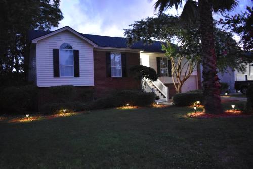 a house with lights in a yard at night at Savannah Lakefront Retreat near Tybee Beach with King Bed and Free Parking in Savannah