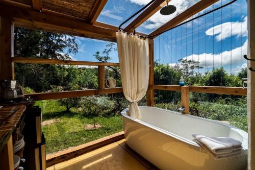 a bath tub in a room with a large window at Casita Acantilado - Timber Frame Tiny House in Monteverde Costa Rica