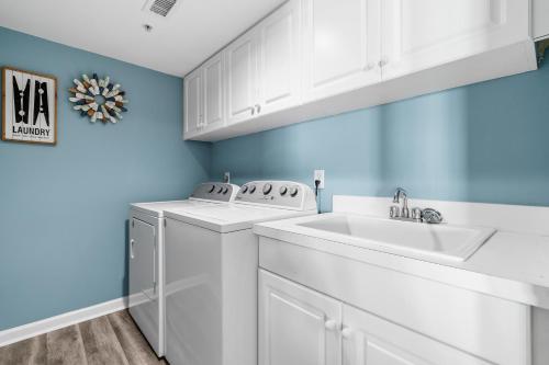 a white laundry room with a washer and a sink at Litchfield Beach & Golf Resort in Pawleys Island