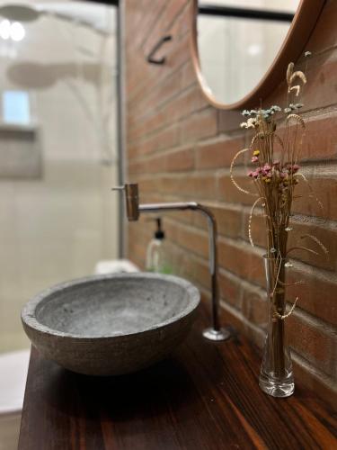 a bathroom with a stone sink and a vase with flowers at Pousada Bem Viver in Nobres