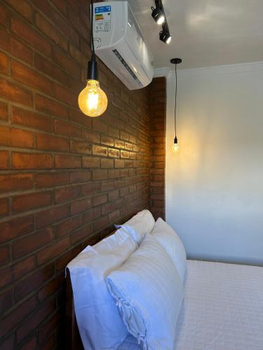 a bedroom with a brick wall and a bed with white sheets at Pousada Bem Viver in Nobres