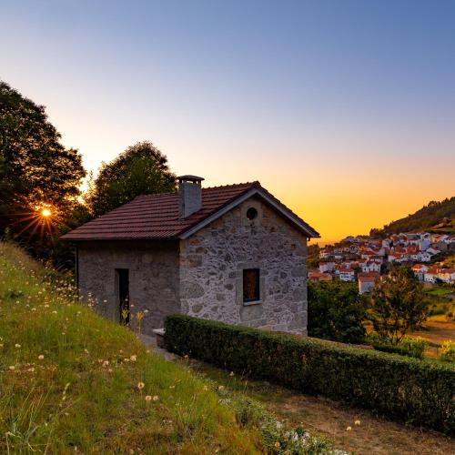 a small stone house on a hill at sunset at Casas do Gato in Valezim