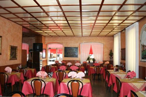 una stanza piena di tavoli e sedie con tovaglia rosa di Hotel San Marco a Bedonia