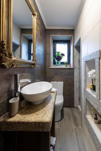 a bathroom with a bowl sink and a toilet at Casas do Gato in Valezim