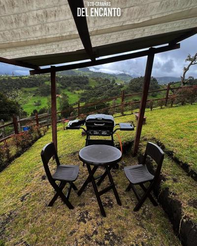 a picnic table and two chairs and a grill under a tent at Eco Cabañas del Encanto, La Calera in La Calera