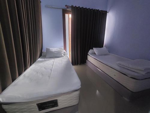 two twin beds in a room with a window at Linobi9e Homestay in Sengkol