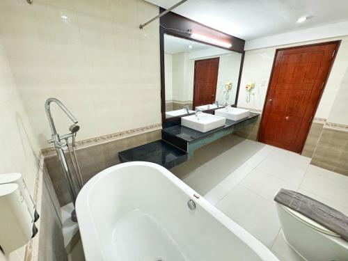 a bathroom with two sinks and a tub and a toilet at Golden Phoenix Hotel Boracay in Boracay