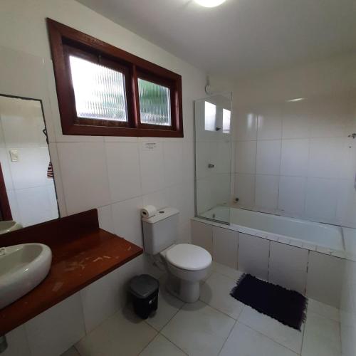 a bathroom with a toilet and a sink and a tub at Villa Tropicale in Salvador