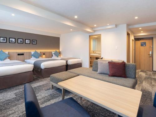 a hotel room with two beds and a couch at HOTEL MYSTAYS Iidabashi in Tokyo