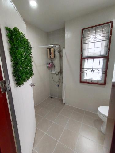 a bathroom with a toilet and a green plant at Be Cute Family and Pet Friendly Stay in Ban Khung Taphao