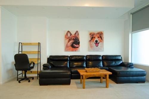 a living room with a black leather couch and two paintings at Tarawera River Lodge Motel in Kawerau