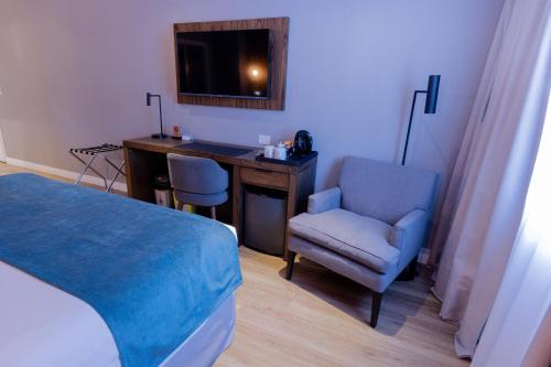 a bedroom with a desk and a bed and a chair at Alto Andino Hotel in Ushuaia