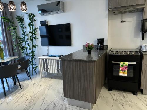 a kitchen with a stove and a tv on a wall at Apártamento Avenida balboa the Sands Vista al Mar Casco Viejo in Panama City